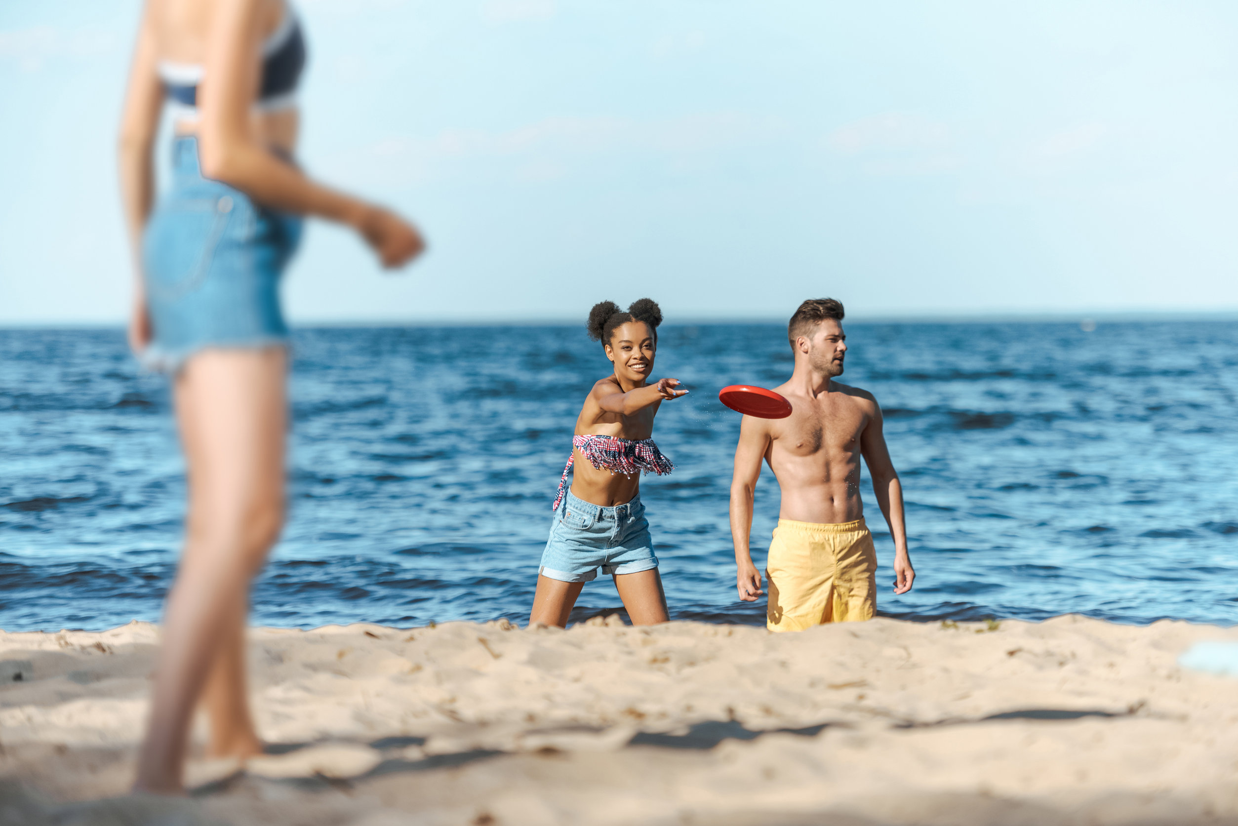 teens playing frisbee on beach