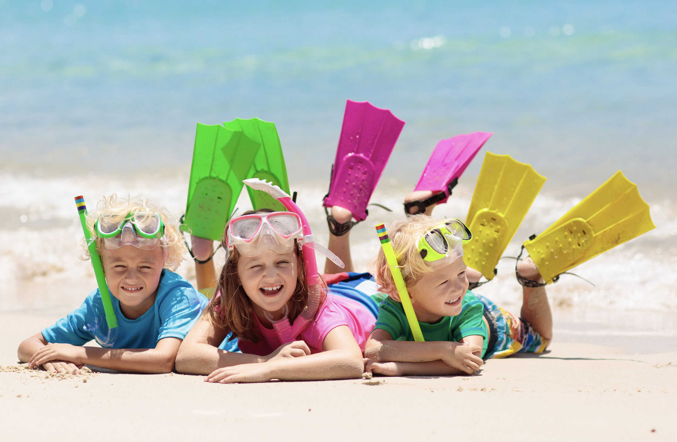 3 kids with snorkel gear on sand