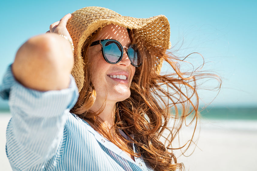 woman at beach with hat and sunglasses