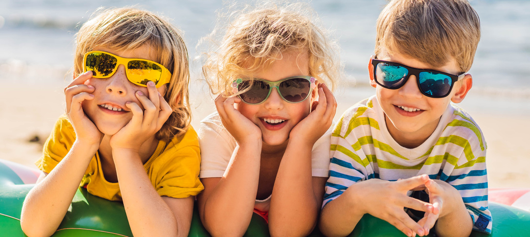 3 kids at the beach wearing sunglasses