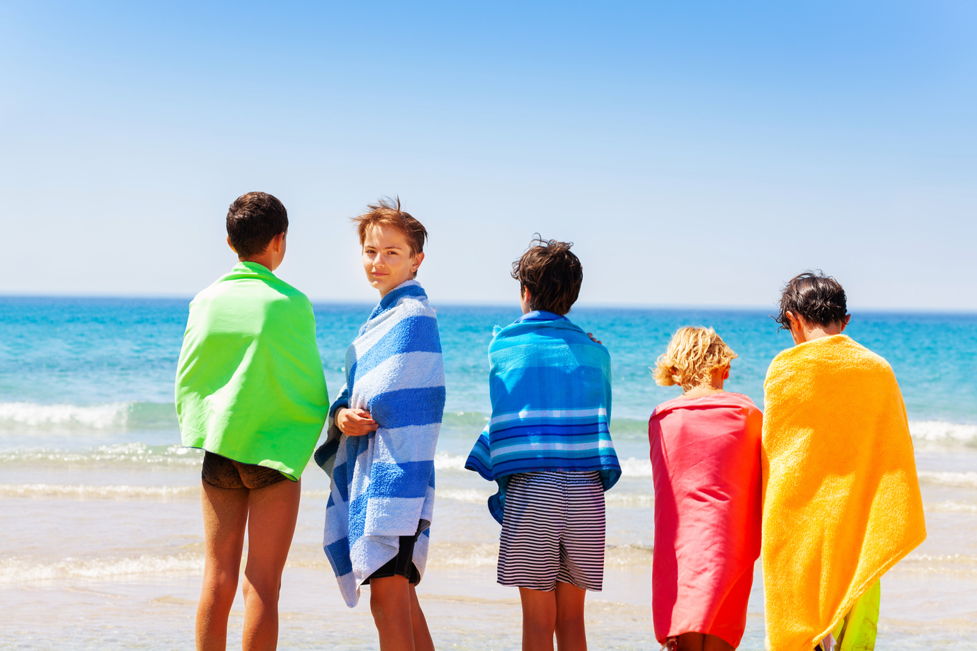 5 kids wrapped in beach towels at the beach